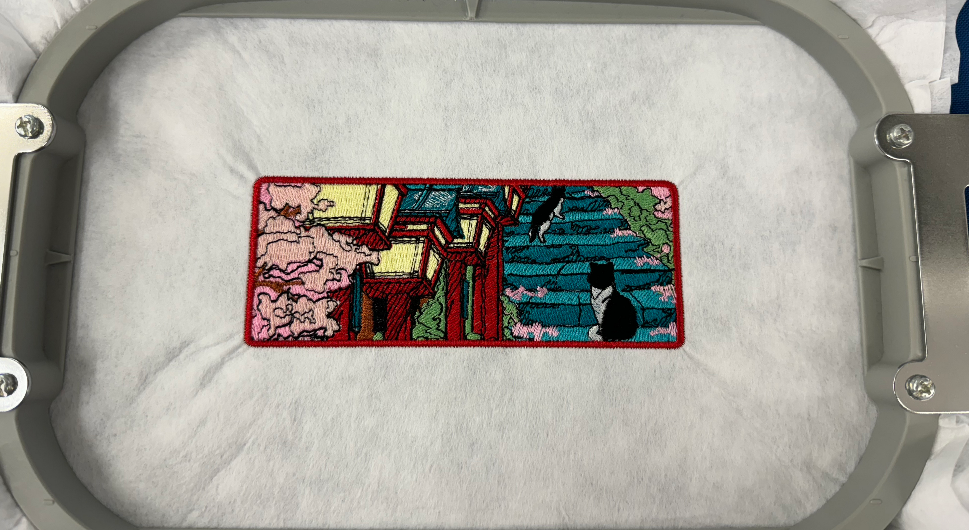 Embroidery hoop with a colorful embroidered design on a white fabric background