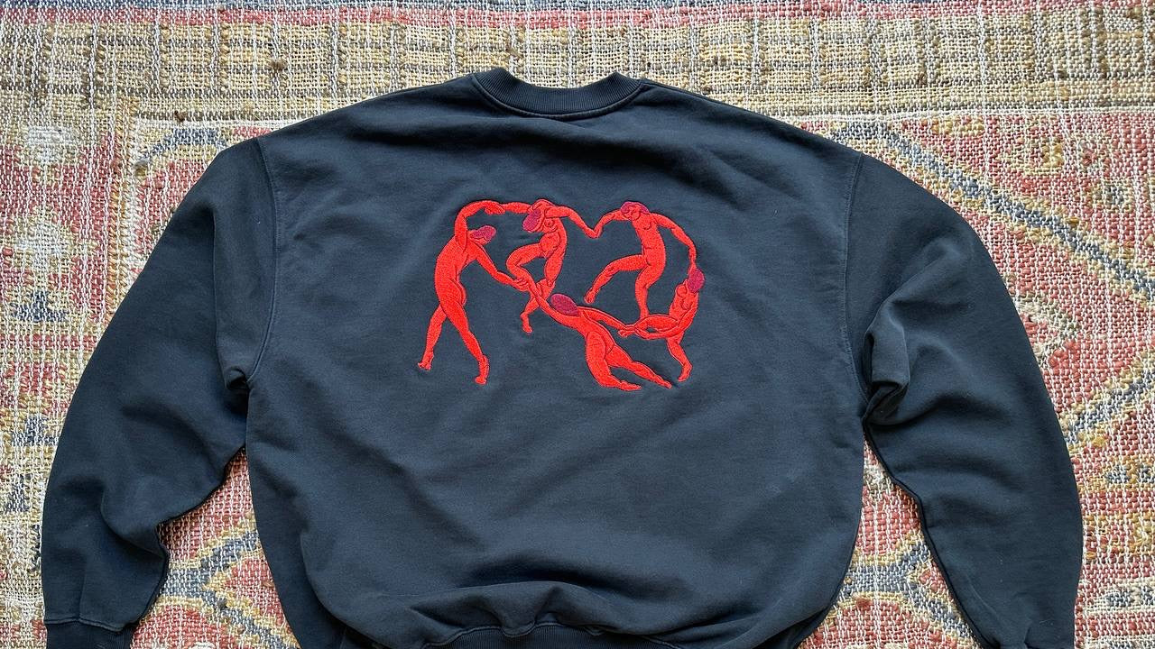 Black sweatshirt with red embroidery design on a patterned surface
